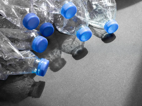 Boş ezilmiş geri dönüşüm plastik içecek su şişeleri üzerinde siyah arka plan ile ışık ve gölge kopya alanı ile temizleyin. Küresel ısınma konsepti.