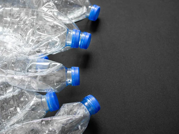 Boş ezilmiş geri dönüşüm plastik içecek su şişeleri üzerinde siyah arka plan kopya alanı ile temizleyin. Küresel ısınma konsepti.