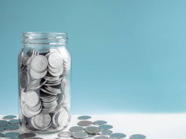 Sikke üzerinde mavi arka plan kopya alanı ile izole cam. Kaydetme para kavramı.