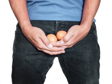 Yumurta beyaz arka plan üzerinde izole pantolon orta kasık üzerinde tutan adam el.