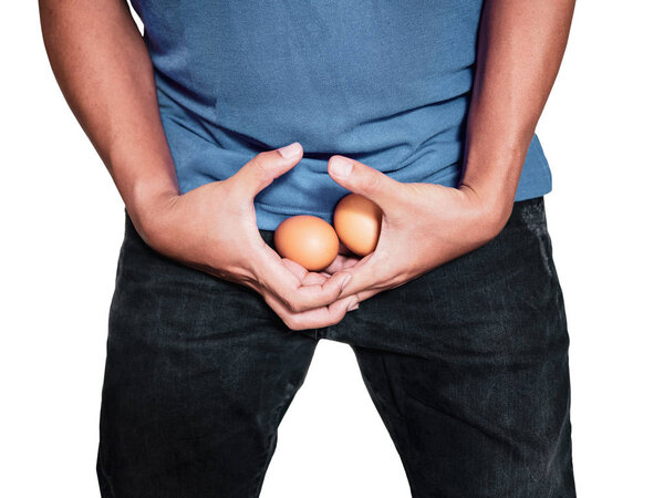Man hands holding eggs on middle crotch of trousers with pain action isolated on white background.