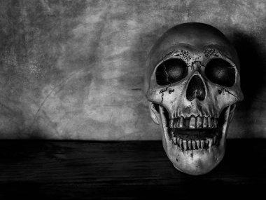 Korku insan kafatası yüz eski ahşap masa ve çimento grunge duvar arka plan üzerinde siyah beyaz stil üzerinde kopya alanı ile.