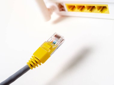 Kablosuz yönlendirici ağ hub izole kopya alanı ile beyaz arka plan üzerinde beyaz kablosuz internet üzerinden bağlayan yakın çekim sarı ethernet kablosu.