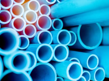 Tüpler Pvc Boru depoda yığılmış. Güneş ışığı ile mavi Pvc borular arka plan.