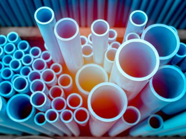 Tüpler Pvc Boru depoda yığılmış. Güneş ışığı ile mavi Pvc borular arka plan.