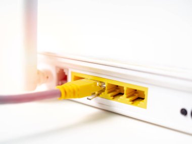 Yakın çekim sarı ethernet kablosu beyaz kablosuz internet üzerinde beyaz arka plan üzerinde izole kablosuz yönlendirici ağ hub'ına bağlı..