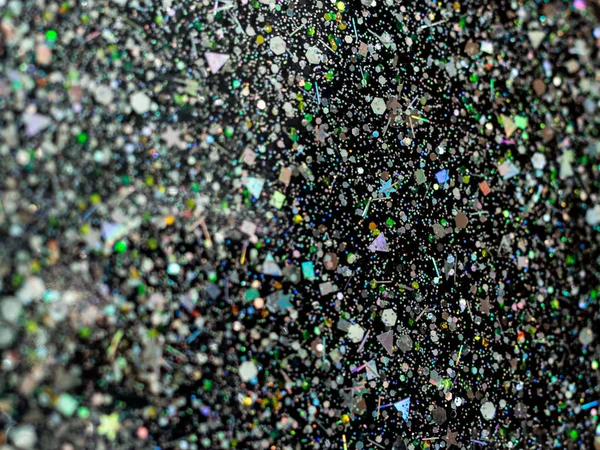 Holographic glitter on black background. Abstract art multicolor glitter background.