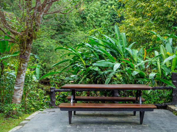 Standard outdoor table with benches on tropical rainforest background.