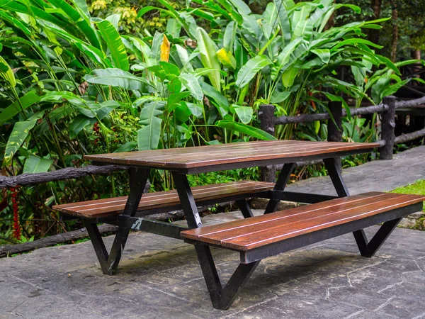 Wooden patio chair reclaimed wood outdoor dining table on tropical rainforest background.