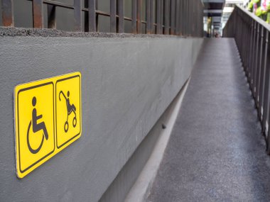 Tekerlekli sandalye ve bebek arabası sarı işareti ve duvar ve arka bina üzerinde rampa.