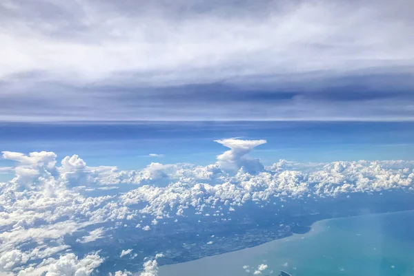 Cloudscape. Beautiful clouds, sky and sea, aerial view from airplane window. Blue sky above the clouds with the ocean.
