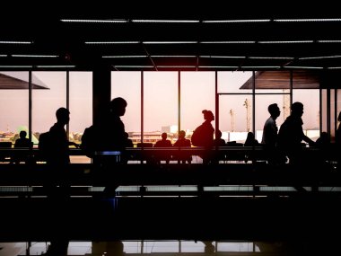 Havaalanı terminal yürüyüş yolcu pencere cam akşam yakınındaki. Geçit devam yürüyüş siluet yolcuları.