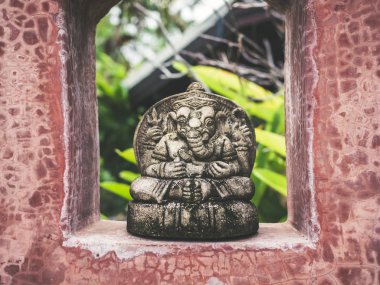 Küçük Ganesha oturan taş heykel üstünde yer üstünde grunge kırmızı çıplak beton duvar ev ve Bahçe arka plan dekorasyon.