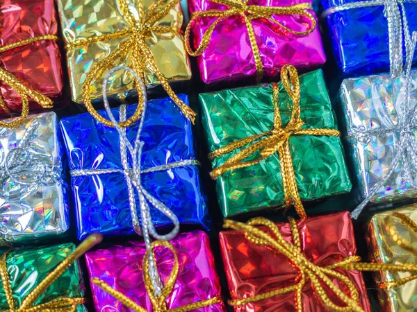 Close-up small colorful gift boxes. Top view of many gifts wrapped colorful shiny paper.