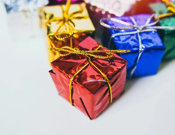 Close-up small colorful gift boxes on white background with copy space. Top view of many gifts wrapped colorful shiny paper.