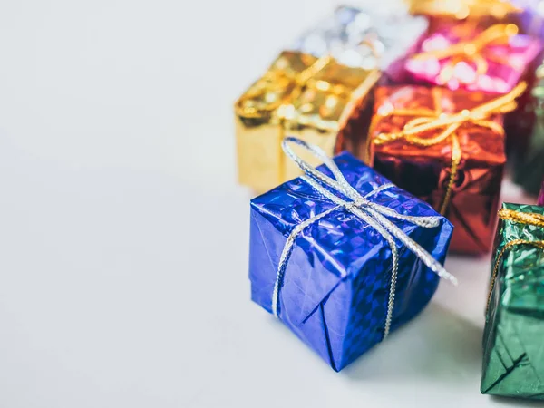 Close-up small colorful gift boxes on white background with copy space. Top view of many gifts wrapped colorful shiny paper.