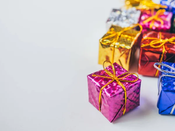 Small colorful gift boxes on white background with copy space. Top view of many gifts wrapped colorful shiny paper.