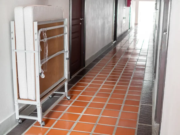 Reserve folding extra bed in front of room on the walkway in hotel.