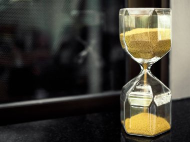 Modern altıgen kopya alanı ile siyah tabloda altın kum tohum ile kum saati. Zaman kavramı geçen ve geri sayım.