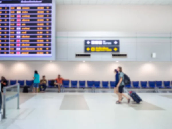 Blurred boarding time monitor screens and passengers in airport hall terminal interior area for arrival passenger.
