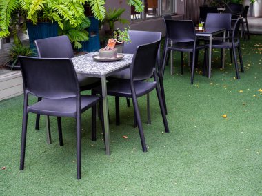 Siyah sandalye ve mermer suni yeşil çim bahçe içinde masaya.