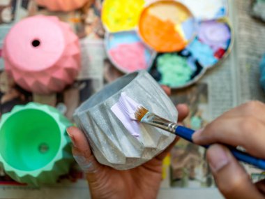 El boyama pastel mor renk mavi boya fırçası ile küçük beton saksı. Küçük geometrik vazo akrilik renk boyama.