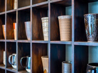 Çeşitli ve modern ahşap raf mavi arka plan üzerinde renkli seramik kupalar.