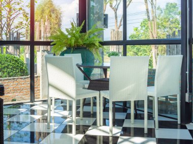 Beyaz örgü sandalye ve kahverengi örgü tablo lokantada. Modern yemek masası cam ev kafe içinde siyah ve beyaz katta güneş gün ayarla.