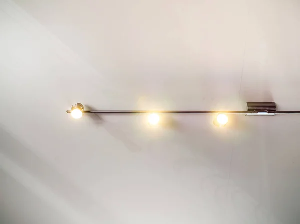 Modern stainless steel track light hanging on white ceiling background.