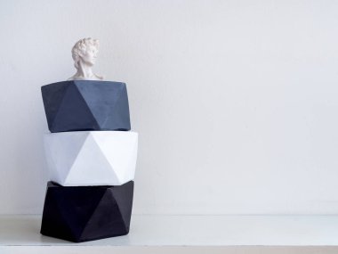 Küçük David heykeli beyaz raf ile beton yetiştiricilerinin modern geometrik pentagon ve beyaz duvar arka plan kopya alanı ile yığını. Ev dekorasyon minimalist tarzı için boyalı beton tencere.