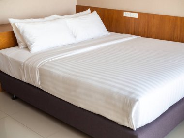Otel yatak odasında dört beyaz yastık ile temiz beyaz yatak