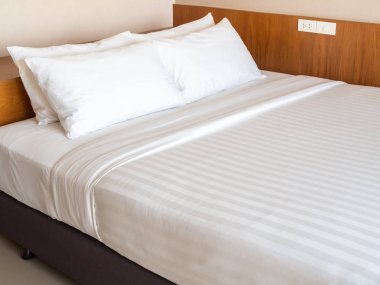 Otel yatak odasında dört beyaz yastık ile temiz beyaz yatak