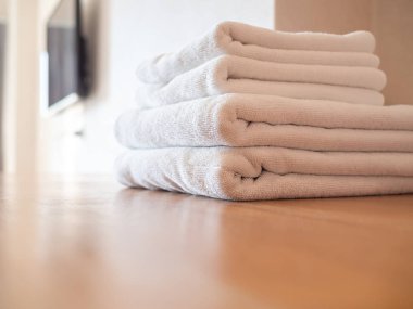 Ahşap yüzeyde beyaz temiz havlular ve beyaz duvar arkaplanı