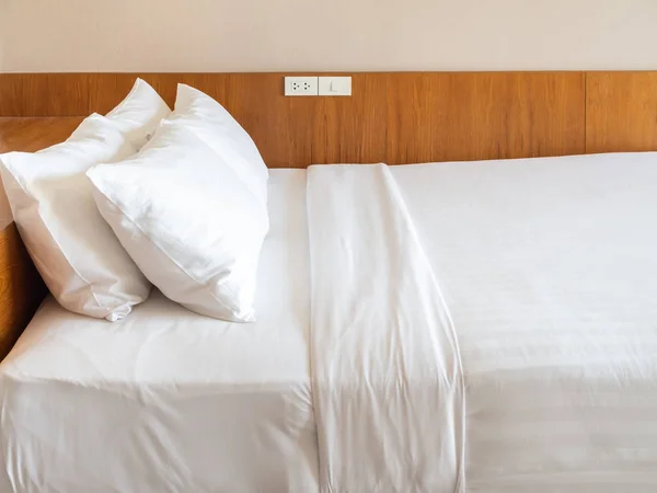 Clean white bedding with four white pillows in hotel bedroom