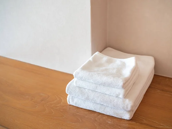 Λευκό καθαρές πετσέτες σε ξύλινη επιφάνεια και λευκό φόντο στον τοίχο — Φωτογραφία Αρχείου