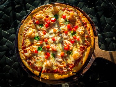 Ahşap pizza tahtasında deniz ürünleri ve domates ile lezzetli dilimlenmiş pizza