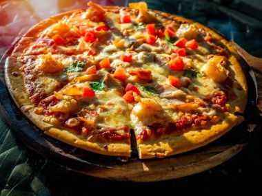 Ahşap pizza tahtasında deniz ürünleri ve domates ile lezzetli dilimlenmiş pizza