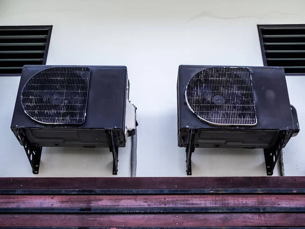 Beyaz duvarda iki eski siyah klima kompresörleri — Stok fotoğraf