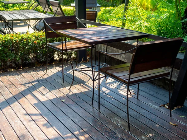 Дерев'яні стільці та дерев'яний стіл на дерев'яній підлозі біля зеленої га — стокове фото