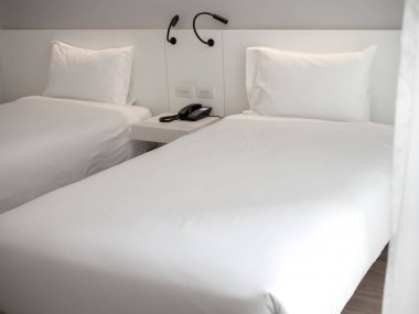 Otel yatak odasında beyaz yastıklı beyaz temiz ikiz yatak
