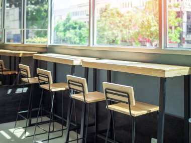 Pencere camına yakın ahşap bar tabureleri ve ahşap masa
