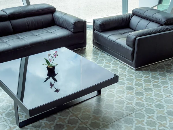 Modern black leather sofa and black glass table on tile flooring