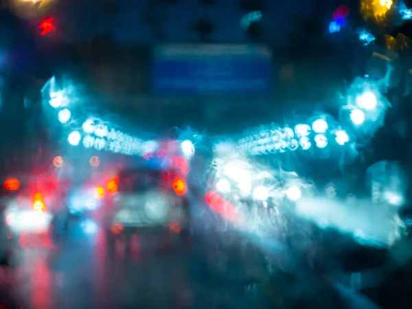 Blurred rain drops on car window with road light bokeh on rainy