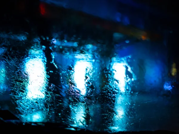 Rain drops on car window with road light bokeh on rainy season a — Stock Photo, Image