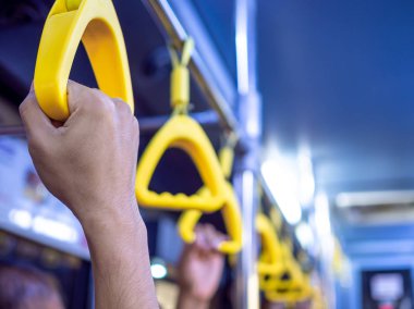 Otobüste sarı sapı tutan yakın çekim el.