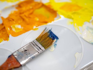 Sarı a ile beyaz plastik sanatçı paleti üzerinde Sanatçı boya fırçası