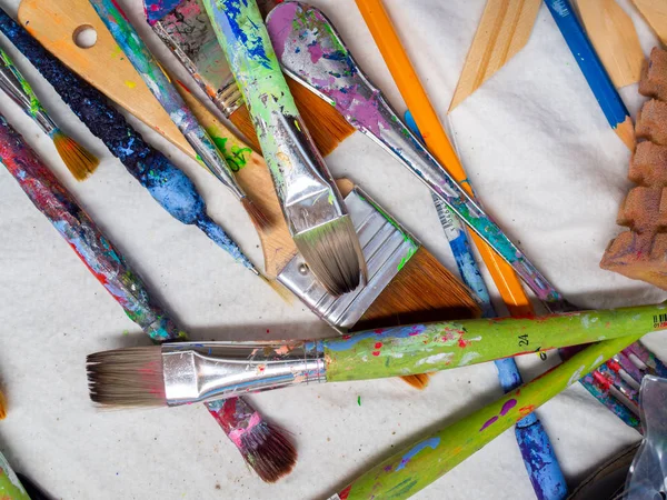 Artist paintbrushes. Flat lay of many artist tools on white fabr — Stock Photo, Image
