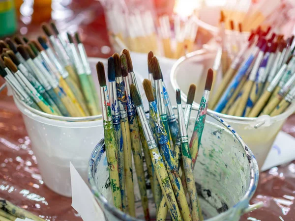 Artist paint brushes. Many artist tools in plastic bucket.