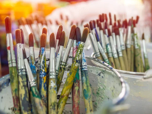 Artist paint brushes. Many artist tools in plastic bucket.