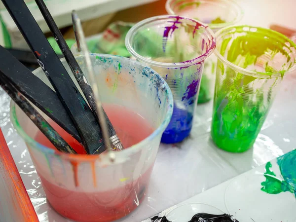 Artist paint brushes in white bucket of water, acrylic colour in — Stock Photo, Image